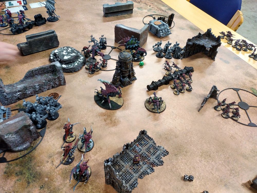 Tyranids and emperor's children forces advance towards the central objective 