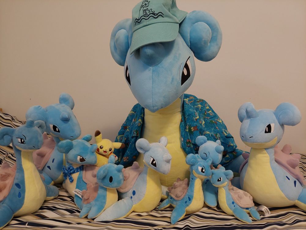 A collection of Lapras plushes, ranging in sizes from small to large