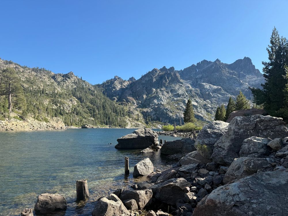 Clear mountain lake surrounded by a rocky shore. Blue sky.