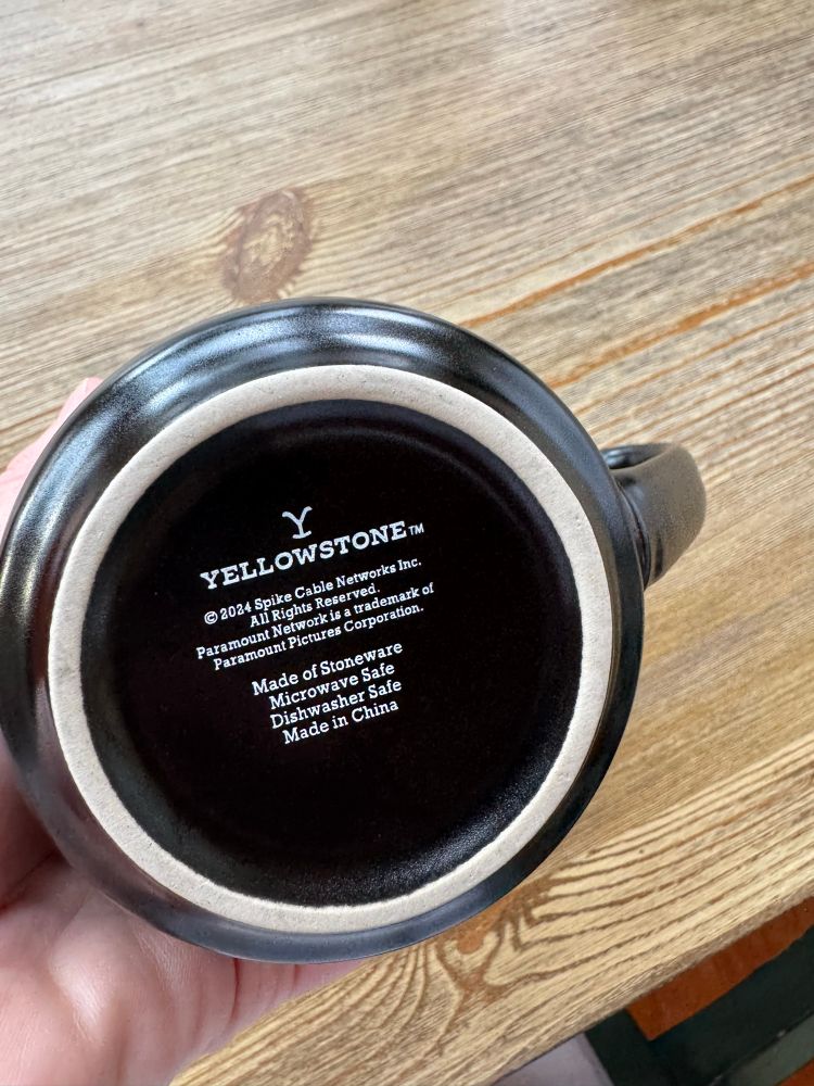 The base of a mass-produced black mug features the logo of the TV show Yellowstone, a soap opera that depicts a highly cliched vision of life in Montana.