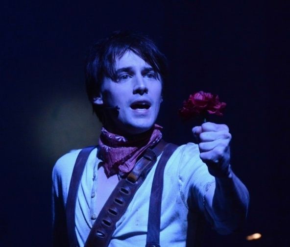 Reeve Carney as a rustic Orpheus in the musical Hadestown, soulfully holding a flower.
Photo by Genevieve Rafter Keddy