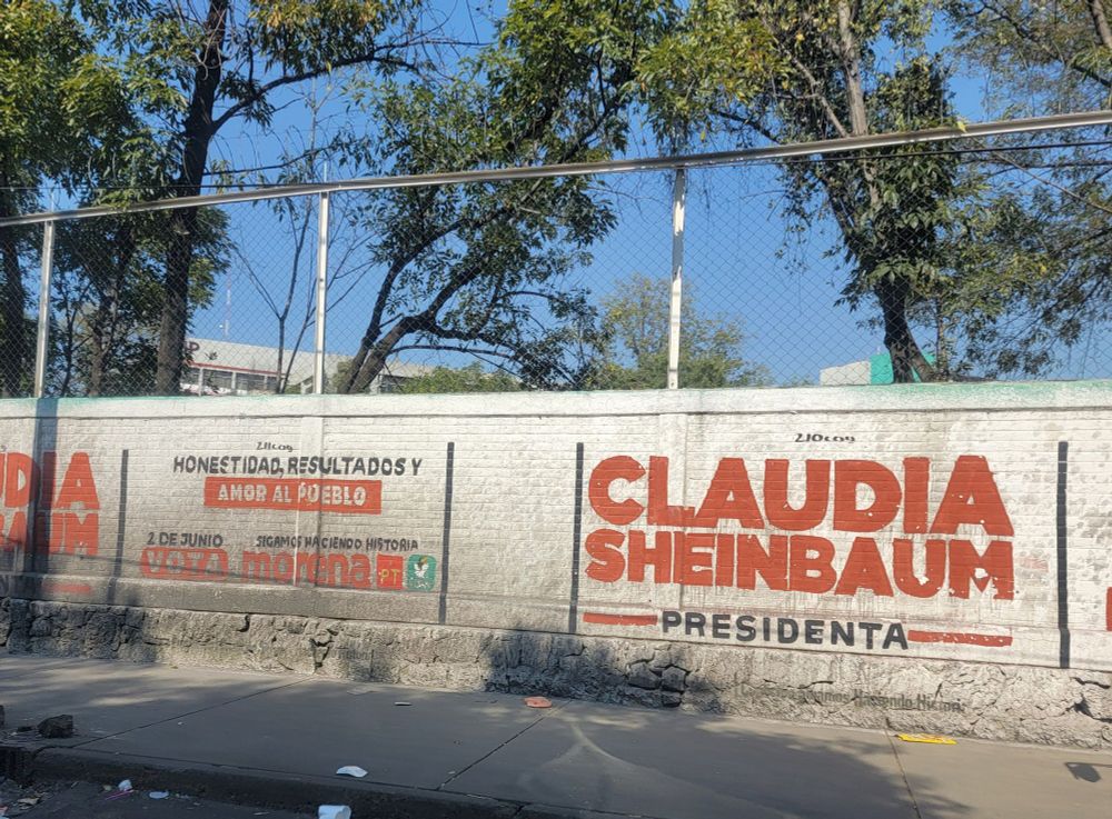 Painted brick wall in Mexico City reads Claudia Sheinbaum Presidenta in red letters on a white background