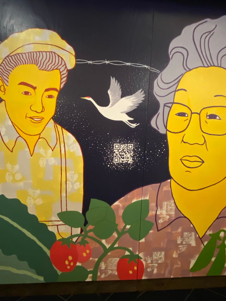 Image of painting of Japanese American farmers onna small building inside the Bellevue library
