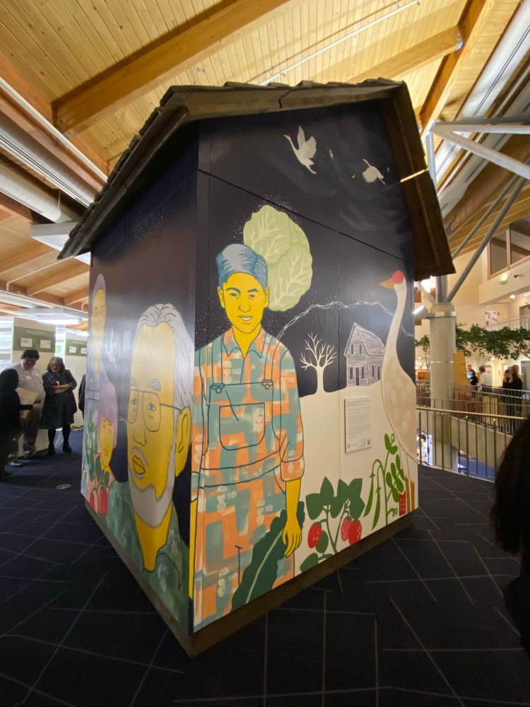 Image of painting of Japanese American farmers onna small building inside the Bellevue library