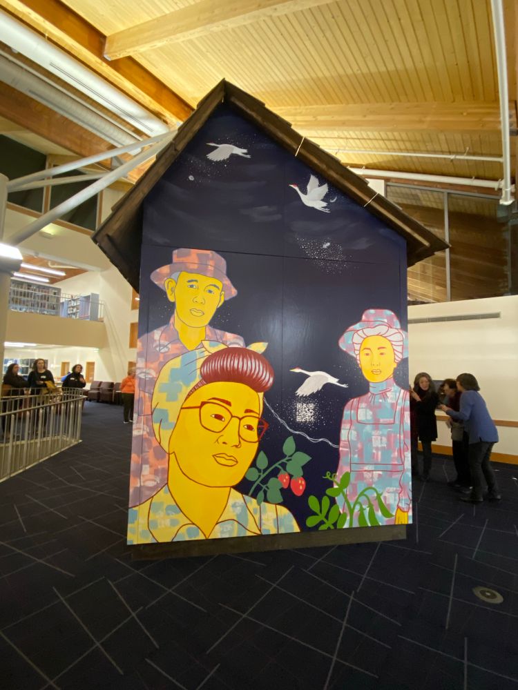 Image of painting of Japanese American farmers onna small building inside the Bellevue library