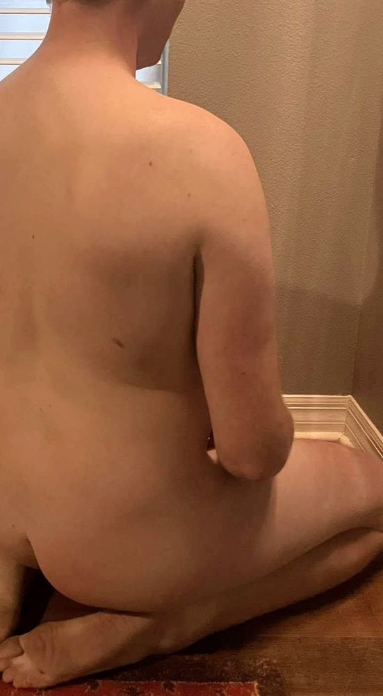 I am on my knees, sitting on my feet, naked. You can see the soles of my feet, ass and back as I stare at the corner of the wall.