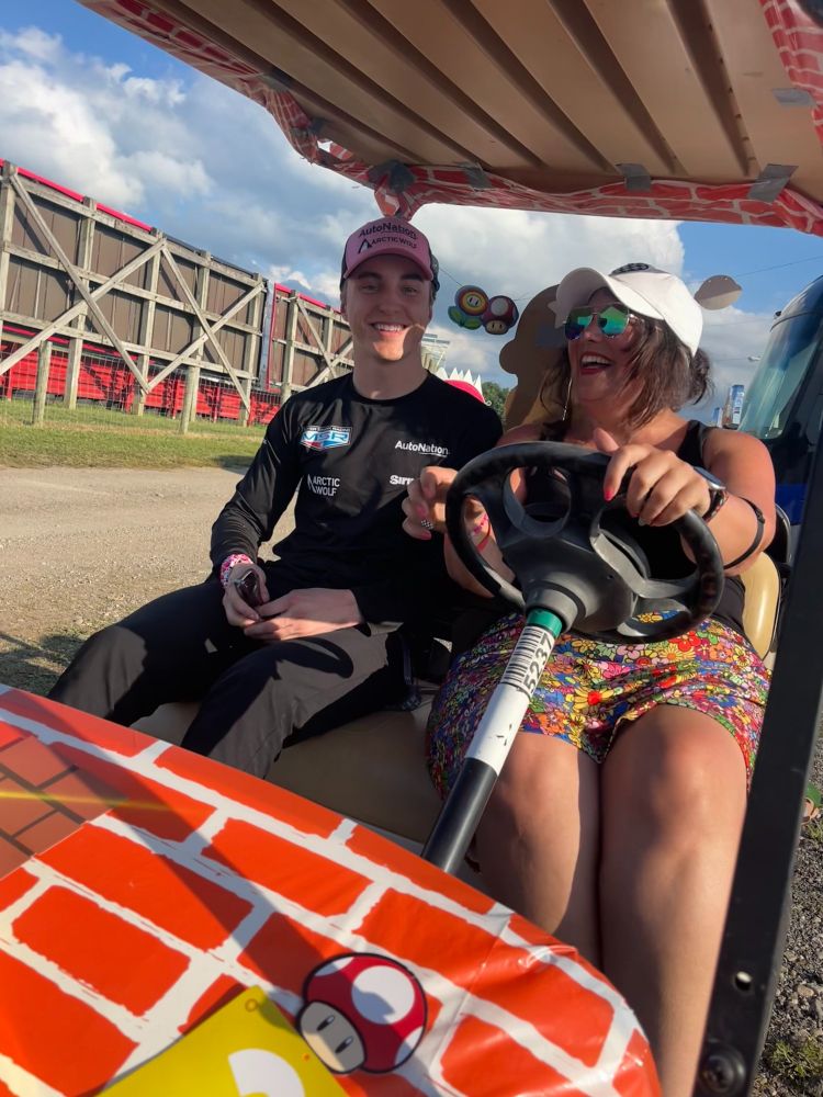 Cassie and David Malukas ride in a Mario-themed golf cart together at the race track