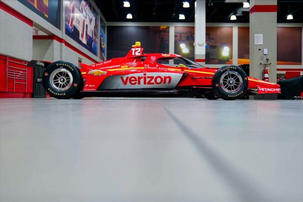 A side view of the #12 Verizon Penske Indycar driven by Will Power. The car is red with white and yellow accents.