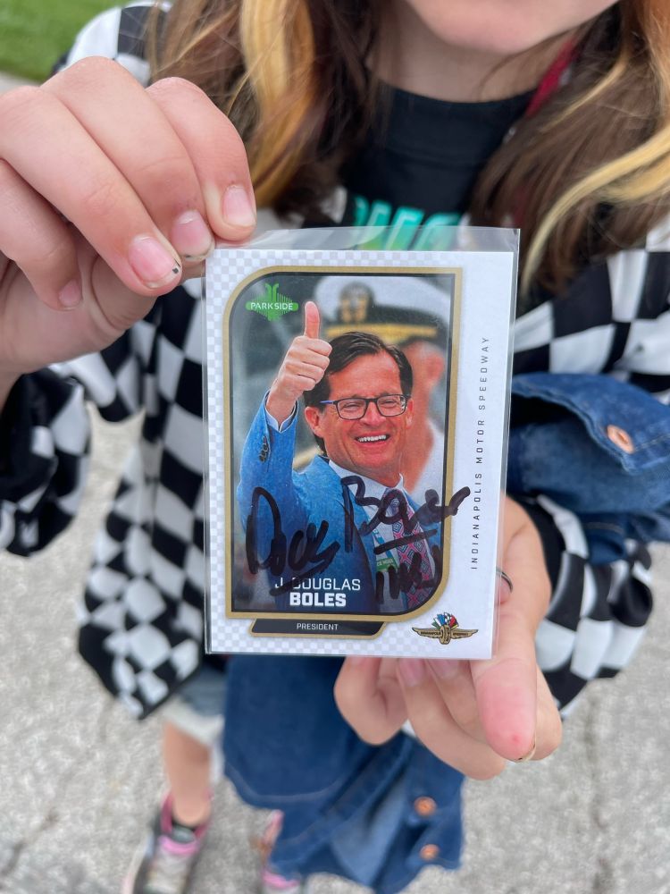 A child holds a Doug Boles trading card towards the camera 