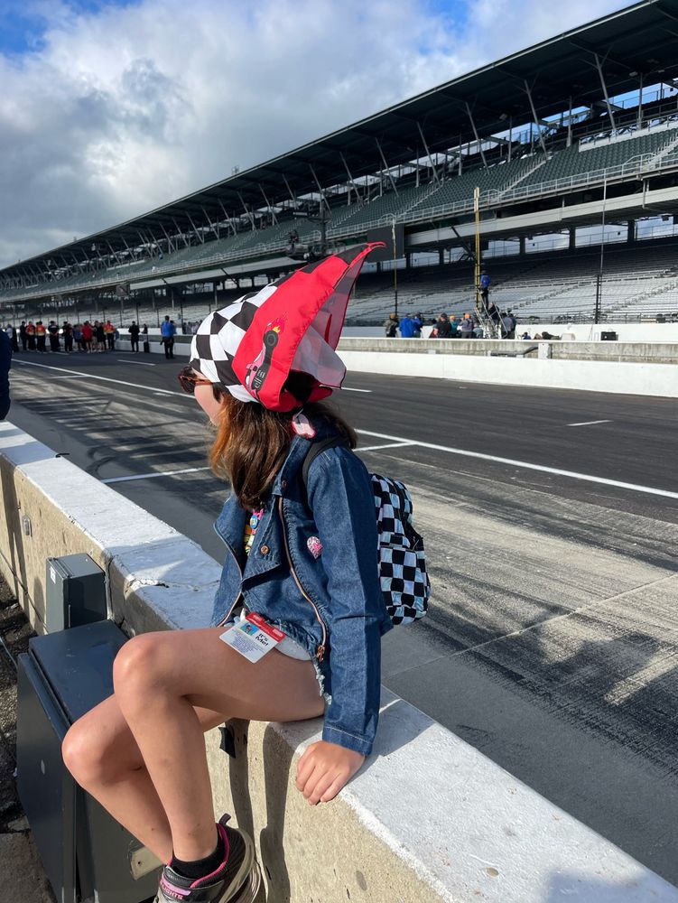 A young girl sits in pit wall at the Indianapolis Motor Speedway looking towards turn one