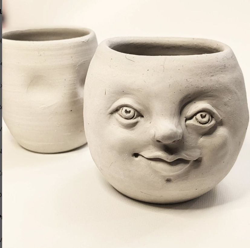 Image is a light grey clay spherical pot with a top opening. It has a genial face sculpted on the front with eyes, nose, lips. Slightly behind it to the left is a smaller more cylindrical pot with two indents for future eyes. They are on a pale coloured background.