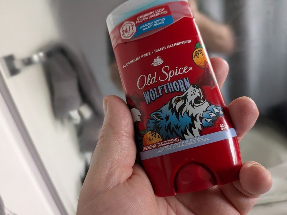 Handsome fellow holding up an Old Spice branded pit stick that says it smells like "Wolfthorn" but really, it's just fake smiles and weakness.