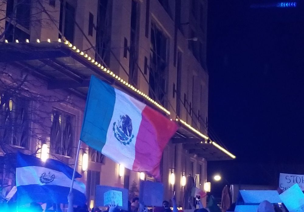Mexican flag and anti-deportation sogns lot by police lights