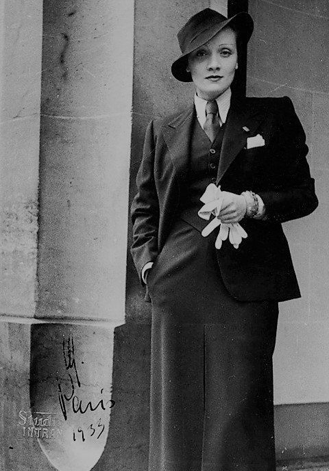 Marlene Dietrich, rocking a dark suit complete with tie and waistcoat.