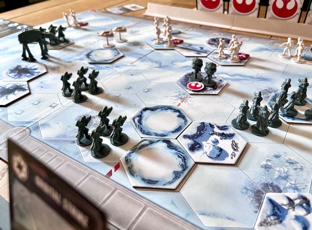 Groups of model infantry on a snowy hex map. Some of the spaces contain hexagon tiles representing different terrain. 