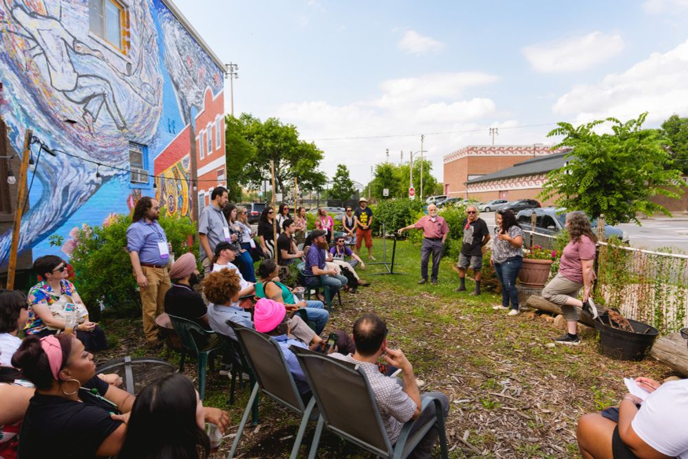 A large group of people outside listening to a presentation 