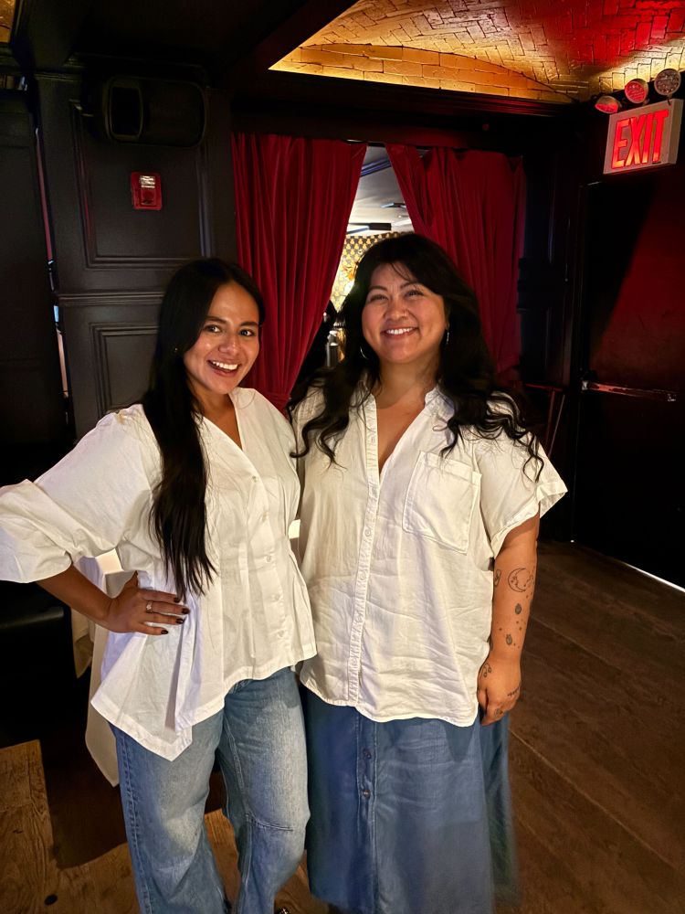 Two people posing for a photo in a dimly lit bar