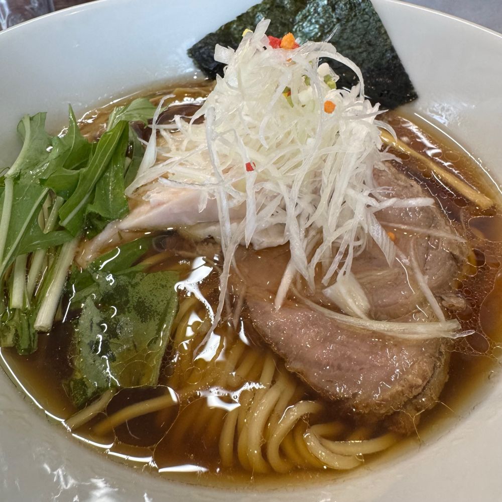 澄んだ醤油色のスープ、白髪ネギ、カラフルな3mmくらいのあられがトッピング、水菜、チャーシュー、鳥チャーシュー、海苔