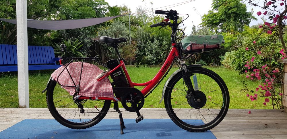 A red ebike with a pink skirt guard over its rear wheel.