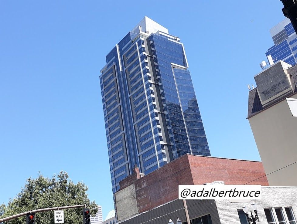 Modern buildings soar, with older buildings, with faded signs, in the foreground. -JBF