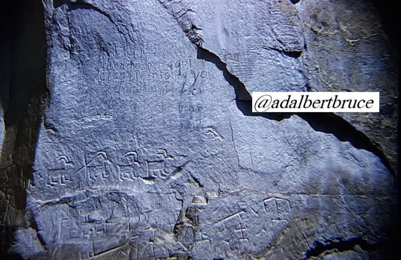 Inscription Rock, showing Native American petroglyphs, depicting mountain goats, in a pattern of four animals. Other carvings and writing appear in the rock as well, along with a large crack. Photo by Bruce W., or Hazel M. Falk, circa 1958. -JBF