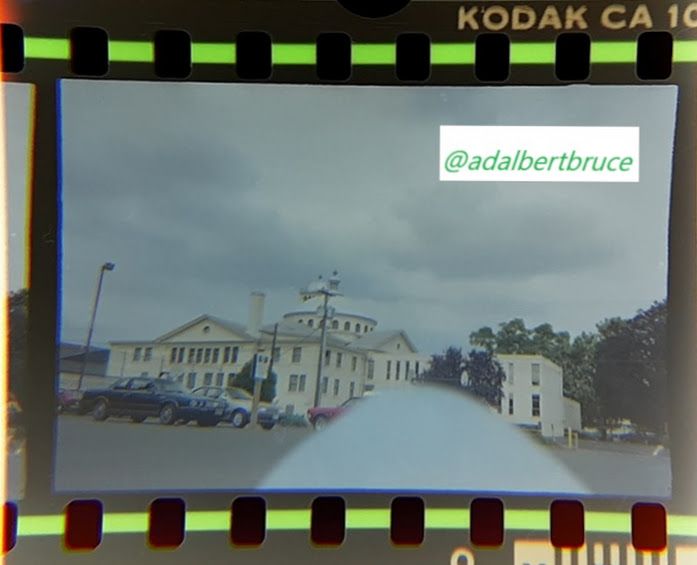 A view of some neoclassical details of the First Christian Church, in Eugene, Oregon; with lowering, gloomy skies, and part of my finger over the lens. 1988. -JBF
