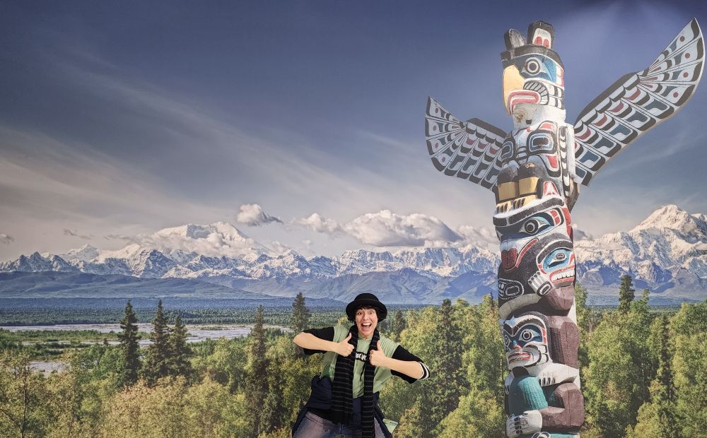 Photo of me smiling and doing two thumbs up in front of a poster which has bizarrely  Photoshopped an American Indian totem in front of the Swiss Alps. This poster is not the Bad Things I am referring to in the post