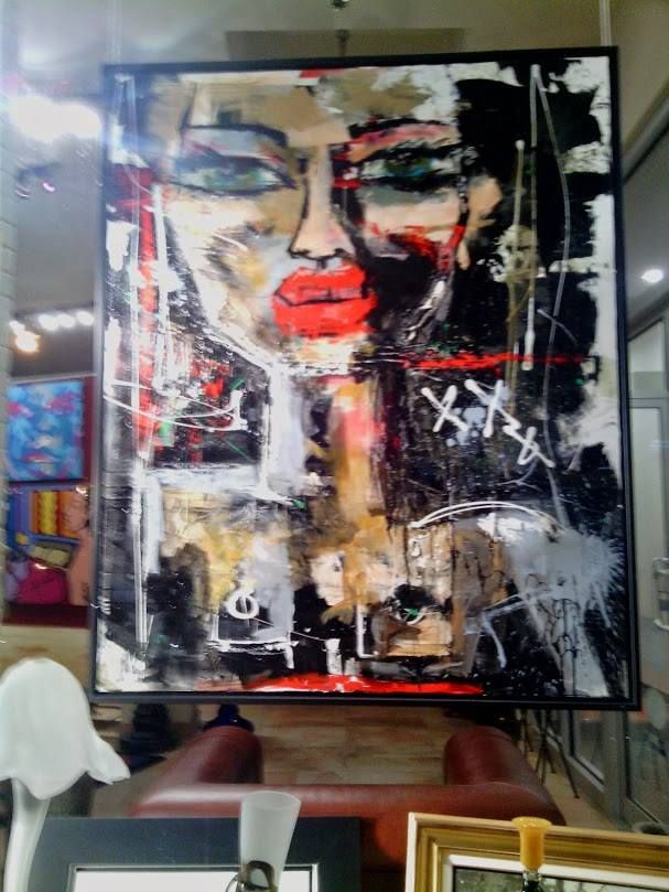 Abstract painting featuring a large face with red lips and intense eyes, surrounded by chaotic brushstrokes and bold colors, evoking mystery and emotion.