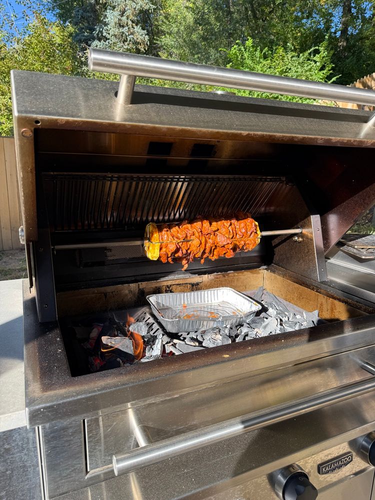 Al pastor cooking on a rotisserie over charcoal 