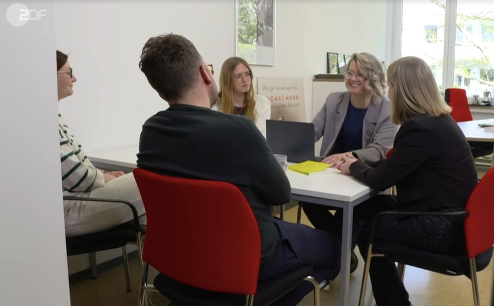 Fünf Personen am Konferenztisch in Diskussion, darunter Lauren Brooks