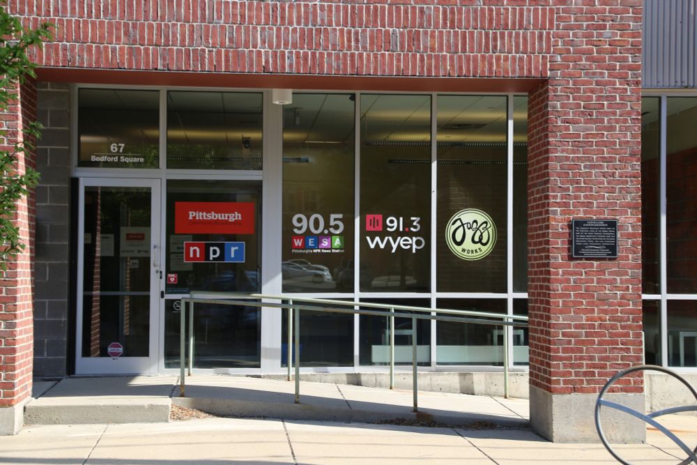 store front with signs in windows for pittsburgh, npr, 90.5 wesa, 91.3 wyep, jazz works