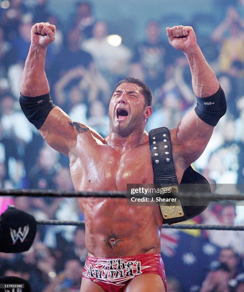 Batista with both arms in the air and the World Heavyweight Championship on his shoulder facing backwards after defeating Triple H at WrestleMania 21. Getty Images. Credit: J. Shearer