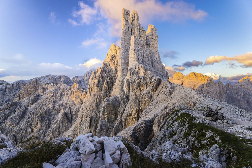 The rocky mountains towers of Torri del Vajolet (Dolomites, 2621 m) at sunset under a beautiful alpine glow and a dark blue sky with little puffy clouds.