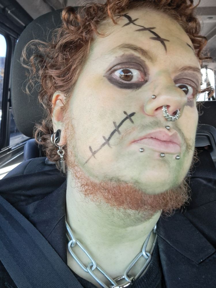 A selfie wearing green face paint with stitches to resemble frankenstein's monster and a heavy metal chain