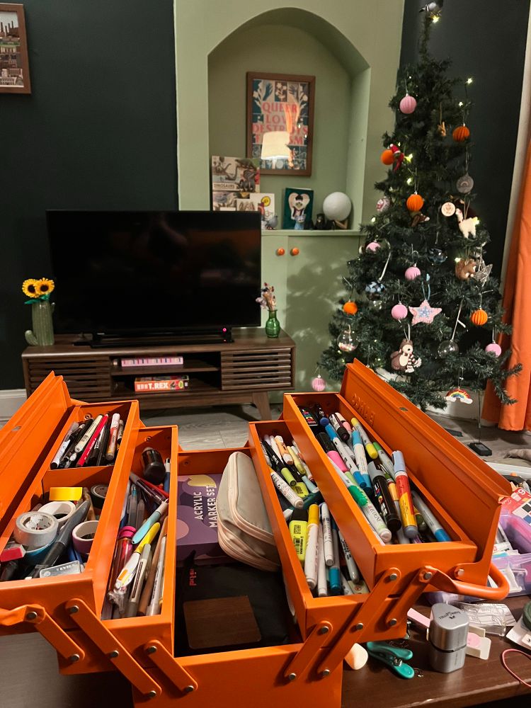 The orange tool box filled with art supplies 