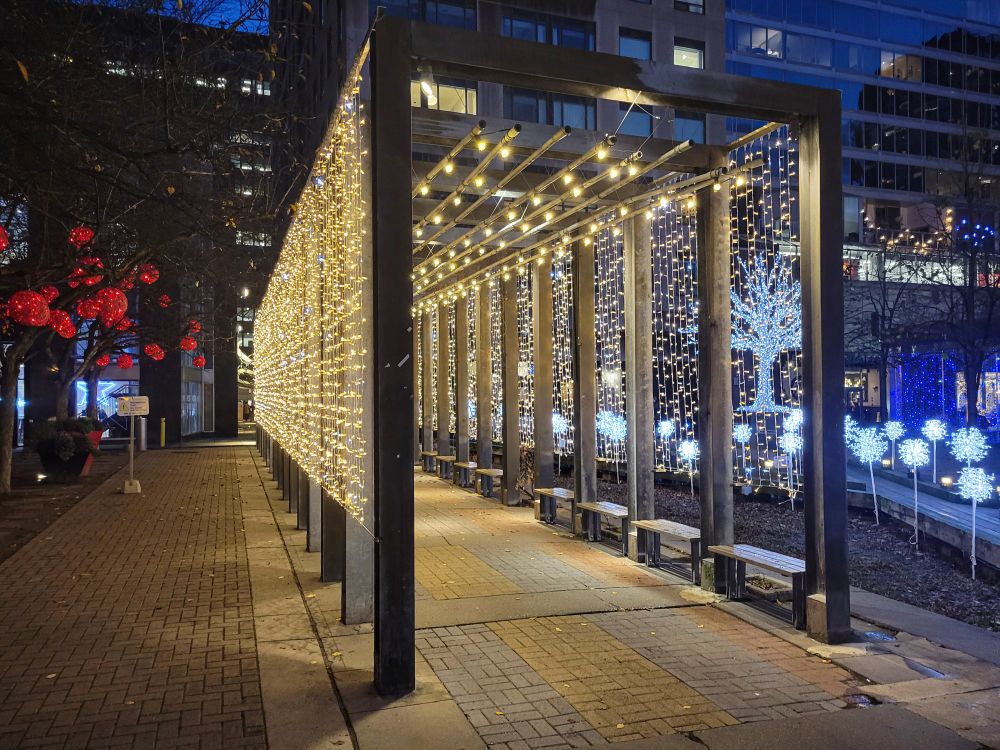 Squared tunnel of yellow string lights, with various other lighted elements in the background