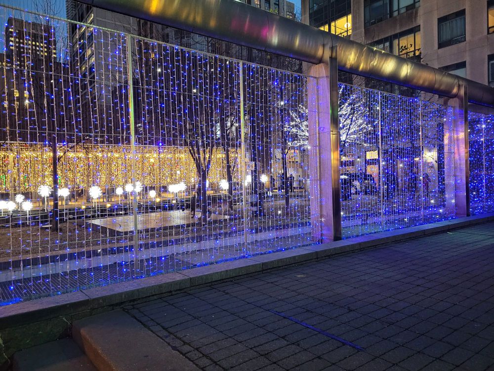 Curtain of blue string lights, with various other lighted elements in the background