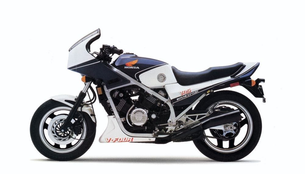 A photo of a 1983 Honda VF750 Interceptor: a 750cc, 90 degree v4 engine, liquid-cooled. An early muscle bike which took awards at track meets. The exposed chassis and large squarish tank set it apart from many other motorcycles (though the tanks suffered from poor durability on the lower pinch seams). This one is two-toned, white and blue/purple. Mine is black and yellow but also in the garage so I can't get a picture right now since I'm not wearing pants.