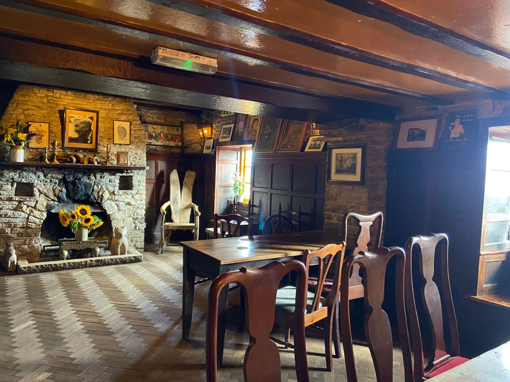 A photo of the inside of a pub with a fireplace and wooden furniture