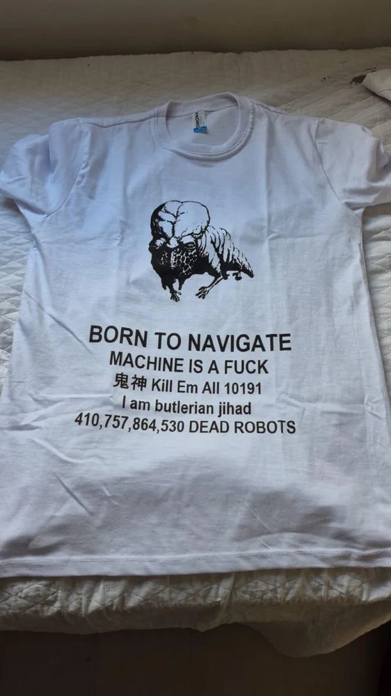 A meme of a white graphic T-shirt. It shows a guild navigator as portrayed in the 1984 cinematic masterpiece titled Dune and directed by legendary outer David Lynch. The text under the image of the navigator reads:

BORN TO NAVIGATE 
MACHINE IS A FUCK
鬼神 Kill Em All 10191
I am butlerian jihad
410,757,864,530 DEAD ROBOTS
