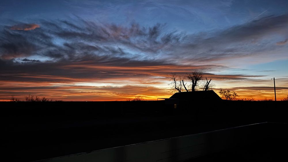 Sunrise behind barn with scattered clouds 