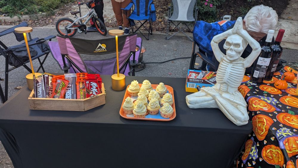 table with candy bars in a wooden coffin, a tray with lemon cupcakes, and a Buddha skeleton