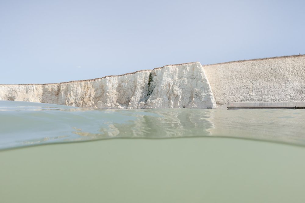 White chalk cliffs as seen from the sea. Some rough and crumbly, some unnaturally well groomed. 