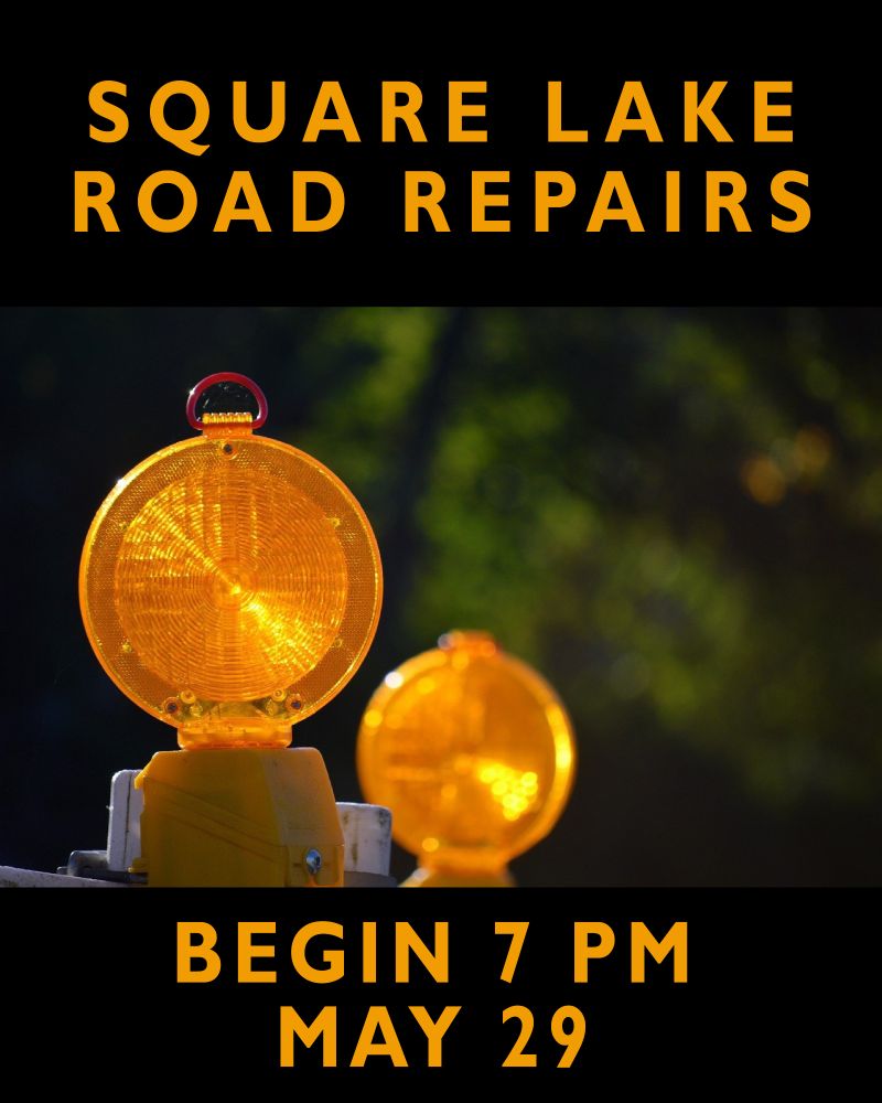 Yellow reflectors atop construction barricades outdoors. Message reads Square Lake Road Repairs Begin 7 p.m. May 29
