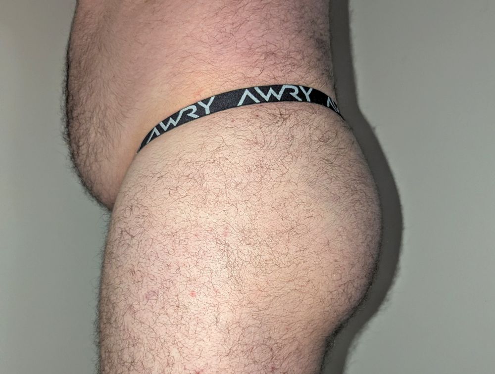 Side view of my tummy and butt, showing off the black and white waistband of the thong. Otherwise, I look close to naked.