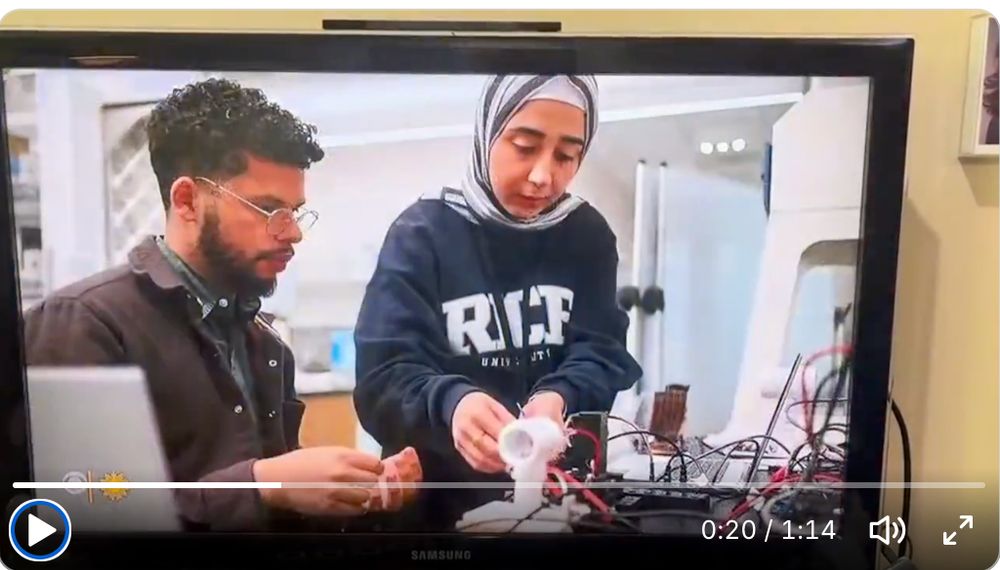 A young male and young female scientist with a head scarf working in a lab.