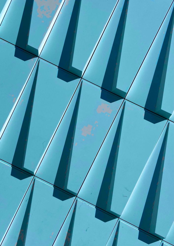 Detail of a wall with a geometric texture. Inverted and cool-colored.