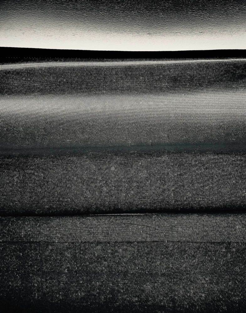 Close texture of fabric curtains hanging in front of a sunny window.