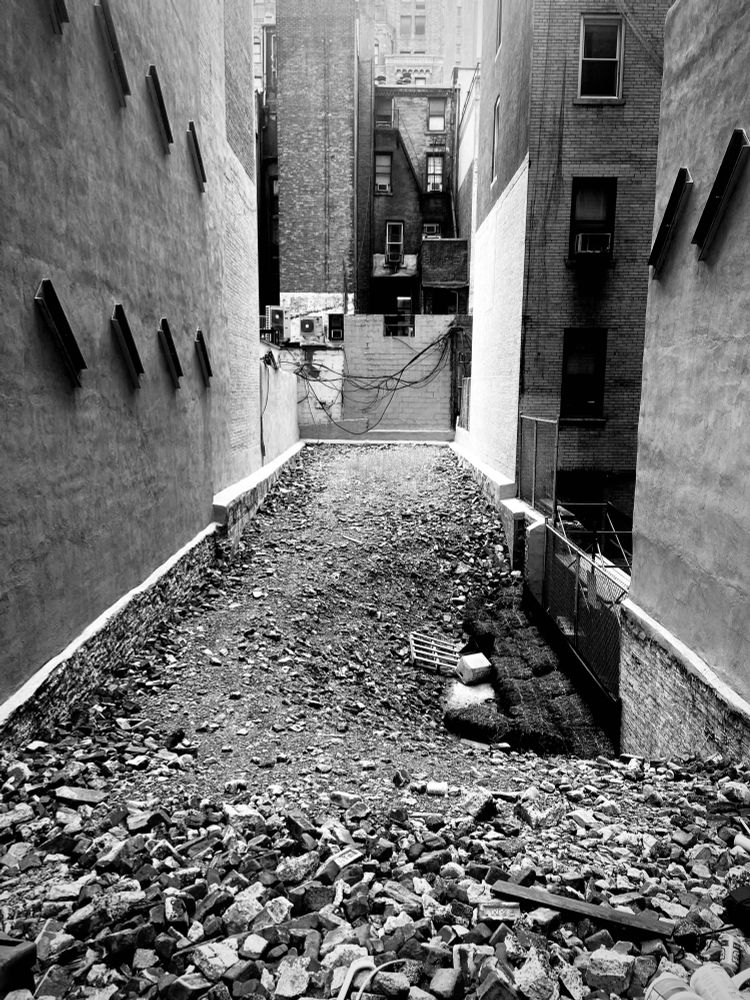 Black and white frame of newly demolished building space in between two standing buildings.