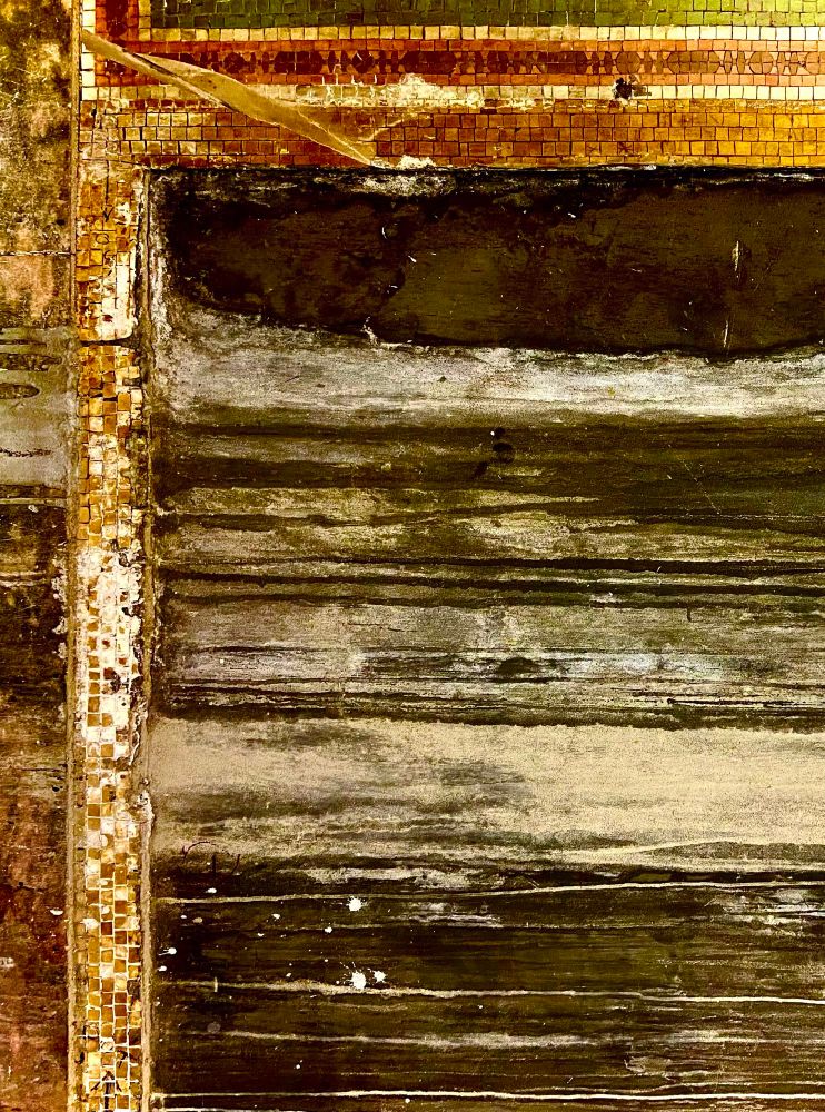 Detail of a wall with worn, displaced mosaic tile and running paint from the Borough Hall Subway station in Brooklyn, NYC. The view resembles an aerial view of a field bordered by intersecting roads.